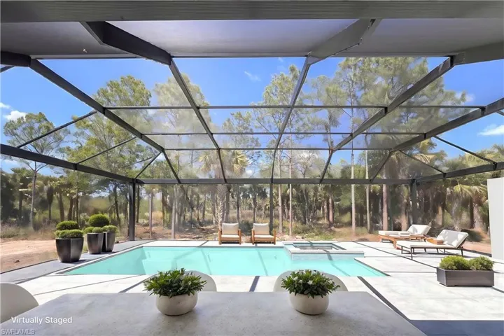 View of pool with a patio area, a pool with connected hot tub, and glass enclosure