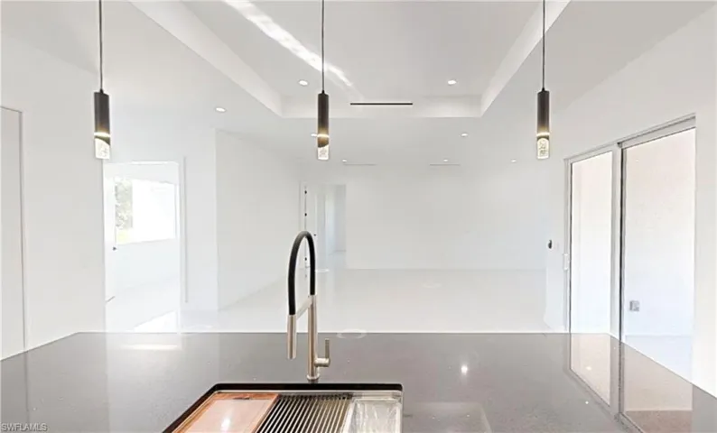 Kitchen with open floor plan, decorative light fixtures, a tray ceiling, recessed lighting, and dark stone countertops