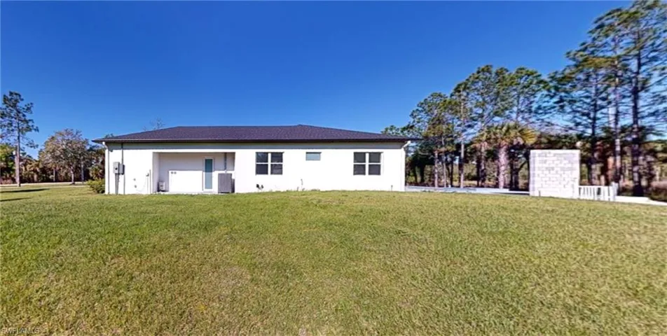 Rear view of house with cooling unit, stucco siding, and a yard