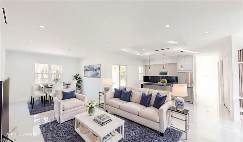 Living room with plenty of natural light, a tray ceiling, and recessed lighting