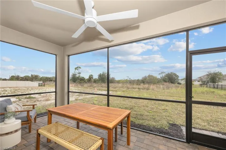 Screened patio featuring a ceiling fan, black frame enclosure, and paver flooring