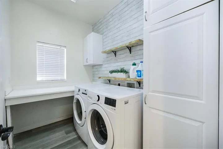 Washroom featuring cabinet space, separate washer and dryer, and dark wood-style floors
