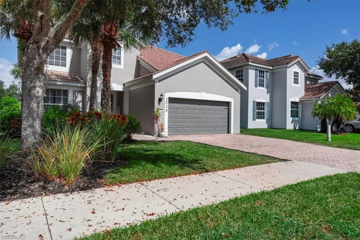 View of front of home featuring stucco siding, decorative driveway, an attached garage, and a front lawn