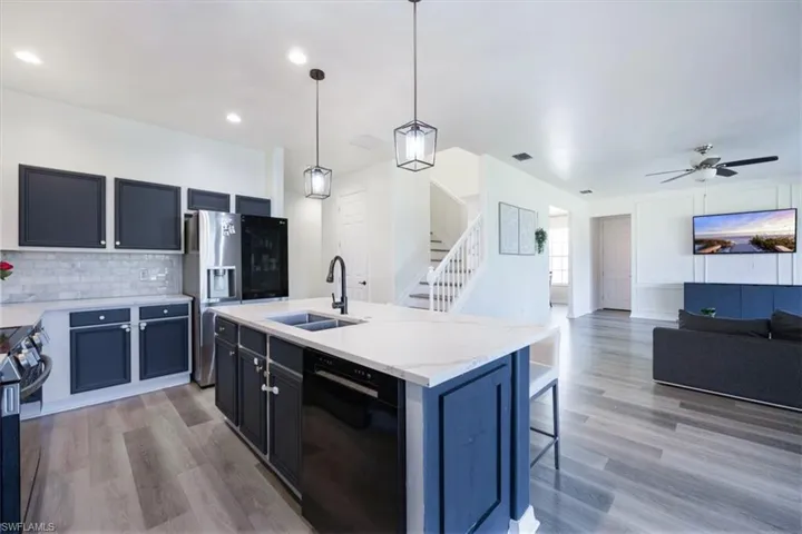 Kitchen with decorative light fixtures, backsplash, stainless steel appliances, a center island with sink, and open floor plan