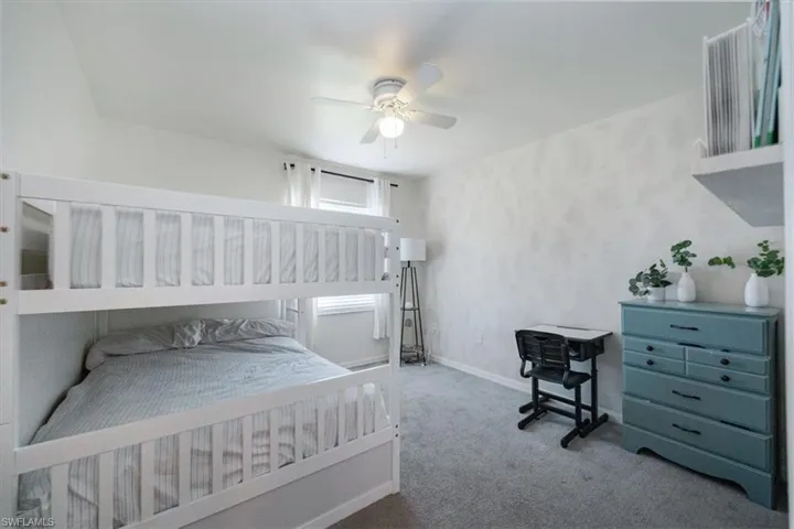 Carpeted bedroom with a ceiling fan and baseboards