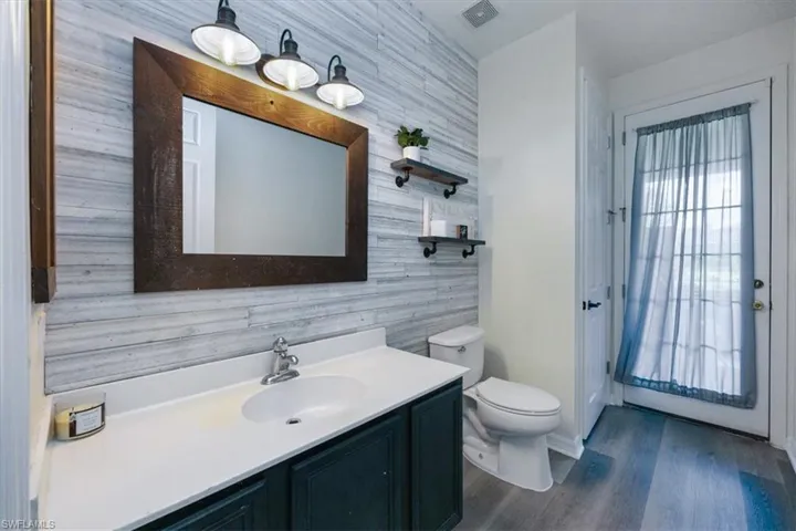 Bathroom featuring dark wood finished floors, vanity, and tile walls