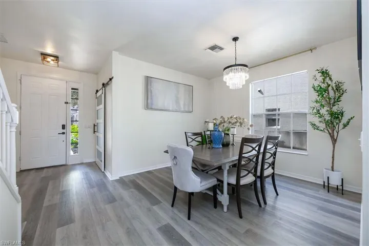 Dining space with a barn door, light wood finished floors, and a chandelier
