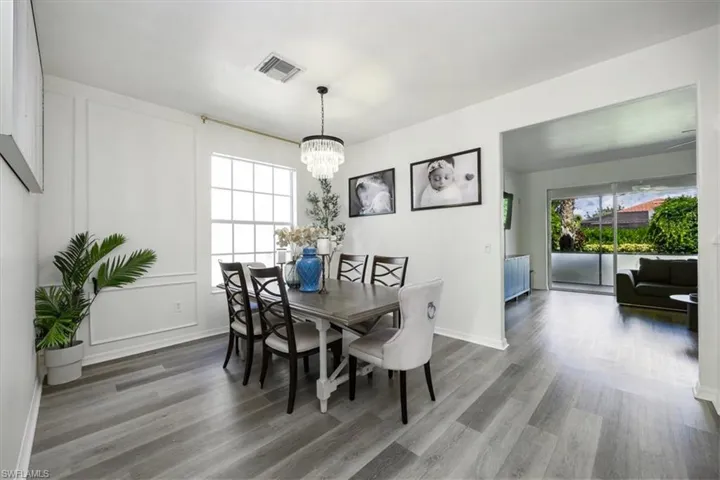 Dining area with wood finished floors, healthy amount of natural light, a chandelier, and a decorative wall