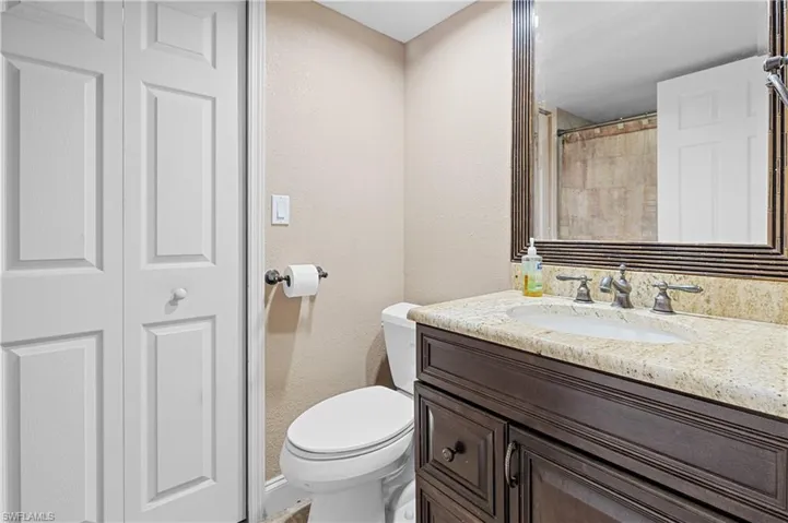 Full bath with a textured wall, vanity, a shower with curtain, and a closet