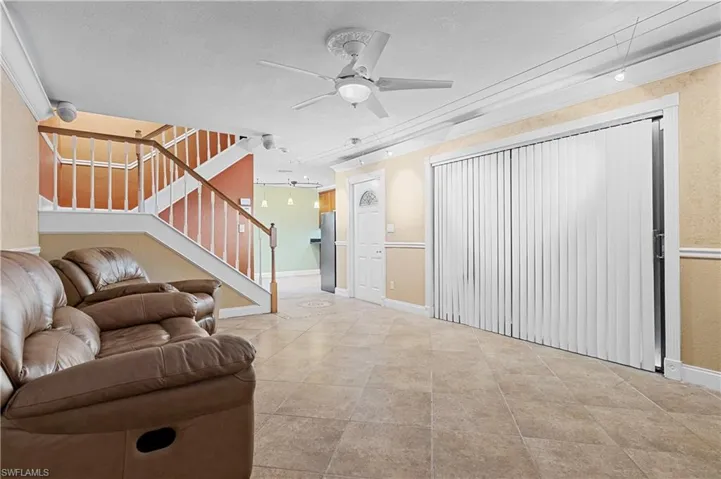 Living room with a ceiling fan, a textured ceiling, and stairs