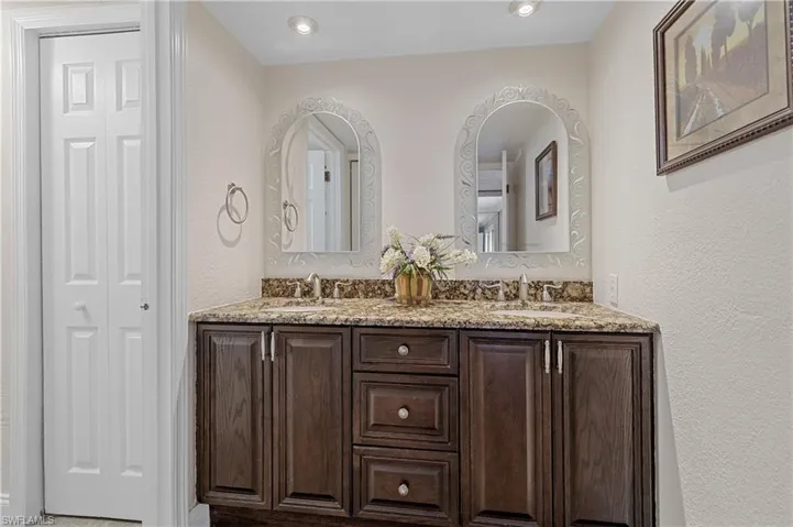 Bathroom with a textured wall, double vanity, and a closet
