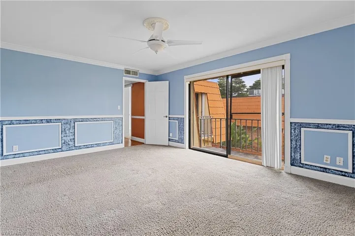 Carpeted spare room with a wainscoted wall, crown molding, ceiling fan, and wallpapered walls