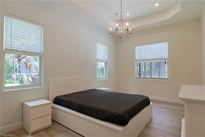 Bright room featuring a tray ceiling with recessed lighting and a chandelier