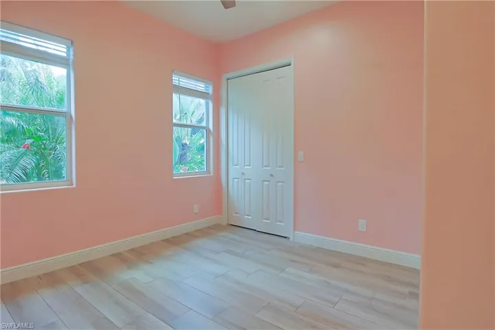 Room featuring light wood-finish flooring, two large windows, and a bi-fold closet door