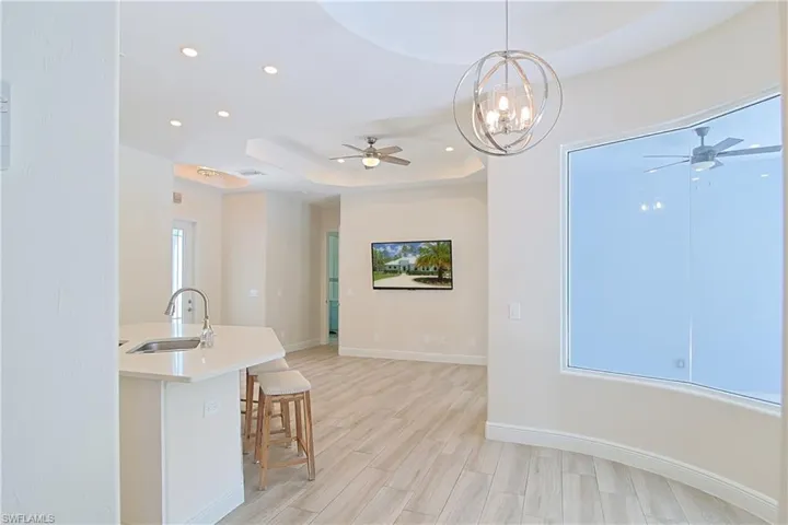 Open-concept living space featuring wood-finish flooring, recessed lighting, and a tray ceiling