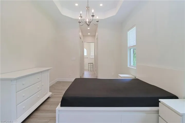 Spacious bedroom featuring a tray ceiling, recessed lighting, and a decorative chandelier