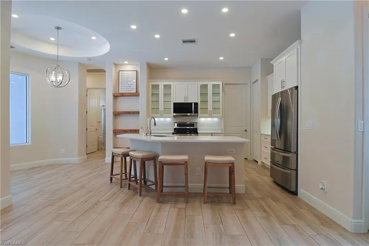 Contemporary kitchen featuring white cabinetry, stainless steel appliances, a center island with bar seating, and wood-finish flooring
