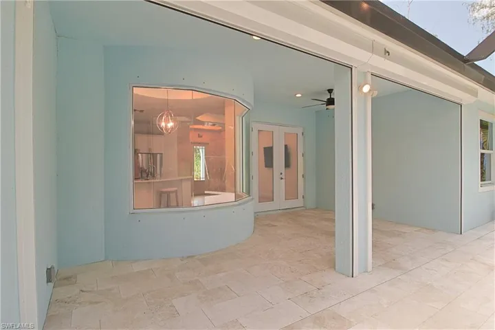 Expansive outdoor patio featuring light-toned tile flooring, an integrated curved window, and recessed lighting