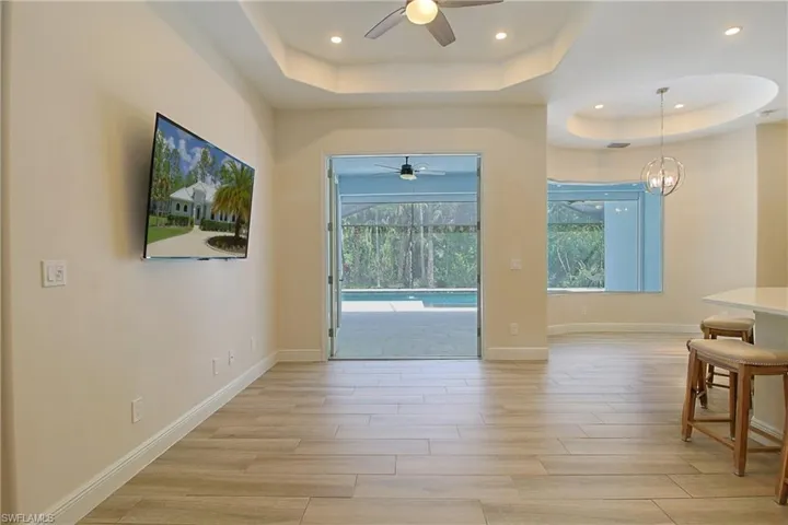 Open concept living space featuring wood-finish flooring and a tray ceiling with recessed lighting