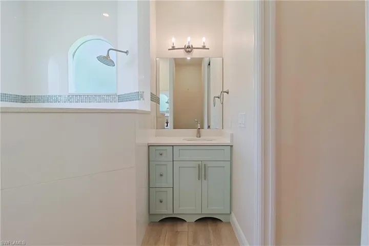Bathroom featuring a light blue vanity with a white countertop and undermount sink, brushed nickel faucet, and a large mirror