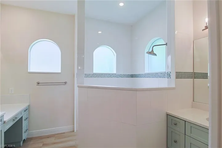 Spacious bathroom featuring a large walk-in shower with dual arched windows and a rain showerhead