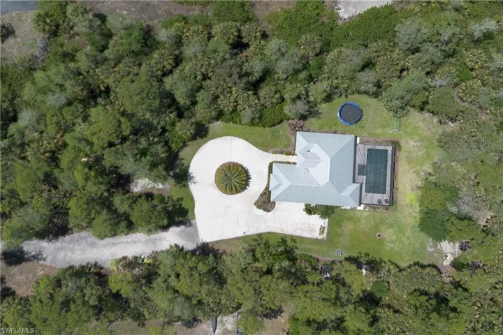 Aerial property overview featuring a private driveway, circular motor court with central landscaping, and a multi-gabled roofline