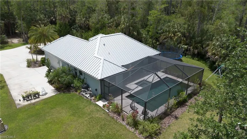 Single-story residence featuring a gray metal roof, light blue siding, and a screened-in swimming pool