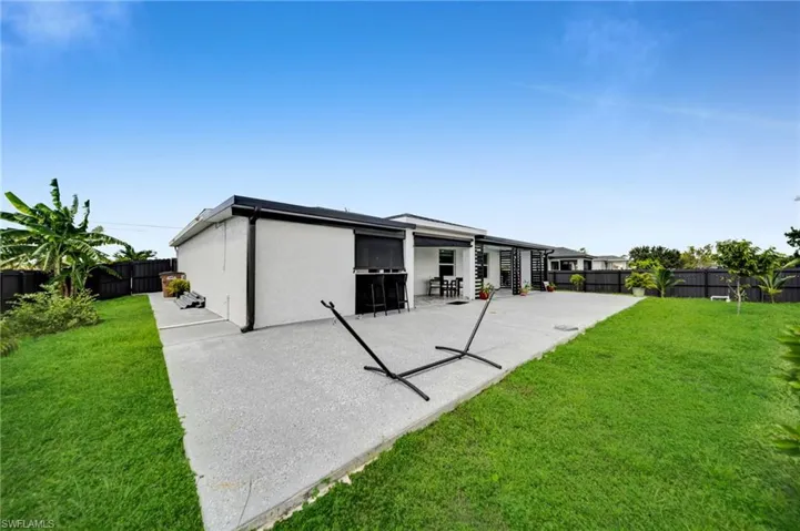 Rear view of house featuring a fenced backyard, stucco siding, and a patio area