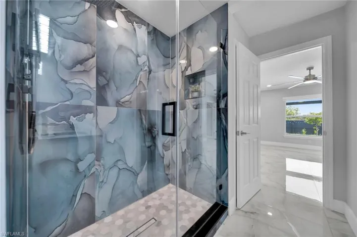 Full bath featuring marble tiled floors, a marble finish shower, and a ceiling fan
