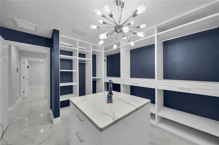 Spacious closet with light marble finish floors and a chandelier