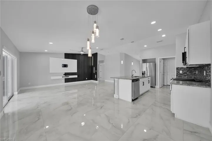 Kitchen with white cabinetry, decorative light fixtures, light stone countertops, open floor plan, and recessed lighting