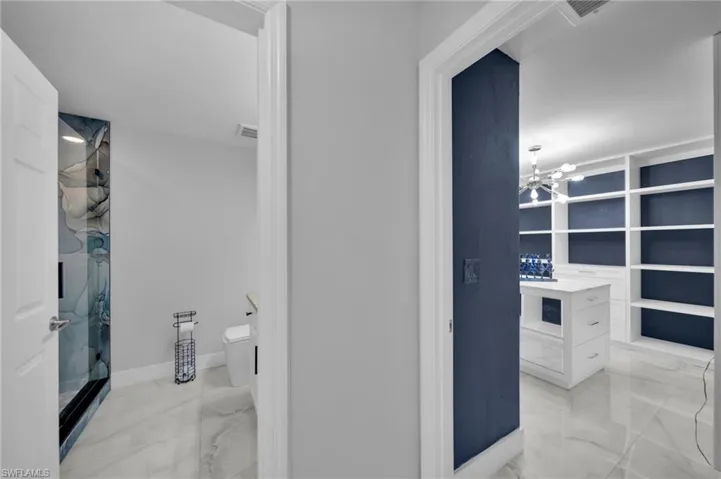 Bathroom featuring light marble finish floors, a chandelier, a shower, and vanity