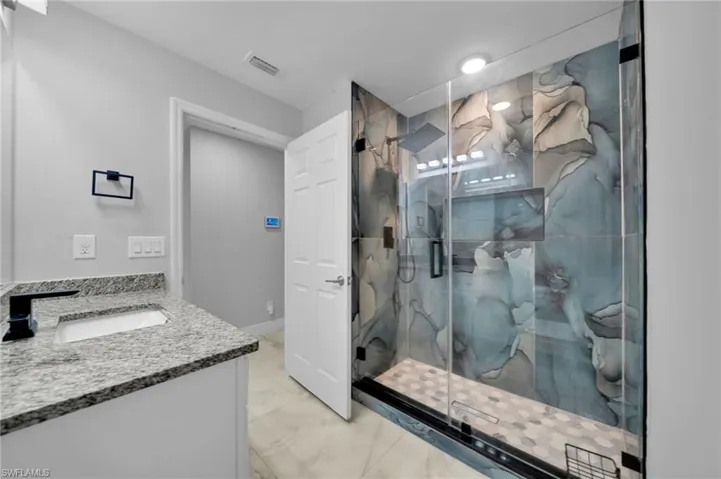 Full bathroom with a marble finish shower, light marble finish flooring, and double vanity