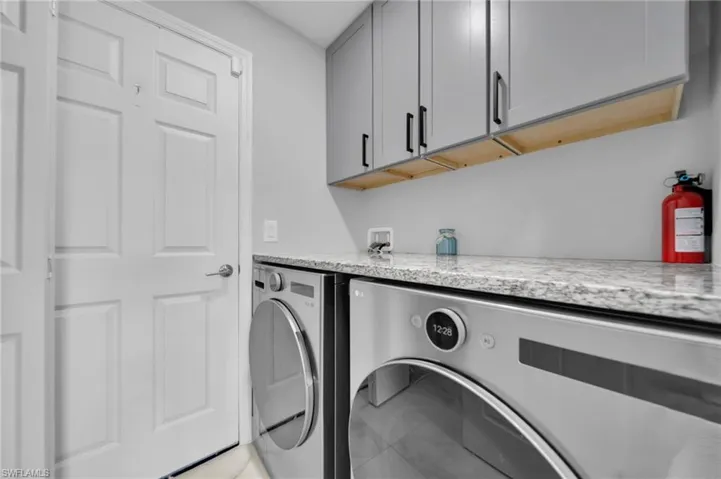 Laundry area featuring cabinet space, light tile patterned floors, and washing machine and dryer