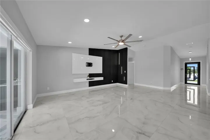 Unfurnished living room with light marble finish flooring, a ceiling fan, and recessed lighting