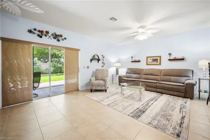 Spacious living area featuring neutral tile flooring, light-toned wall paint, and a white ceiling fan