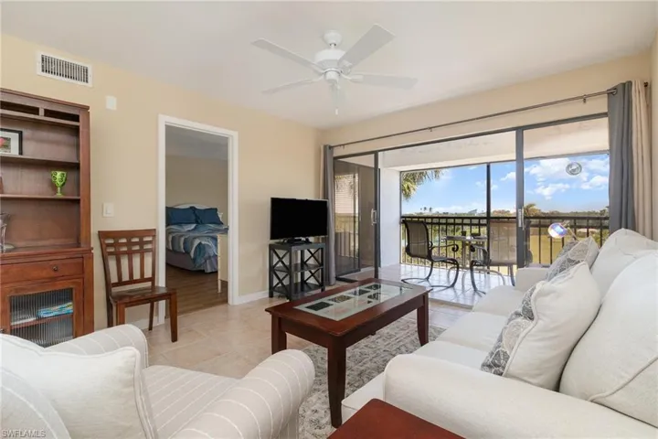 Living Area – Light tile flooring, ceiling fan, and a view of the lanai and pond.