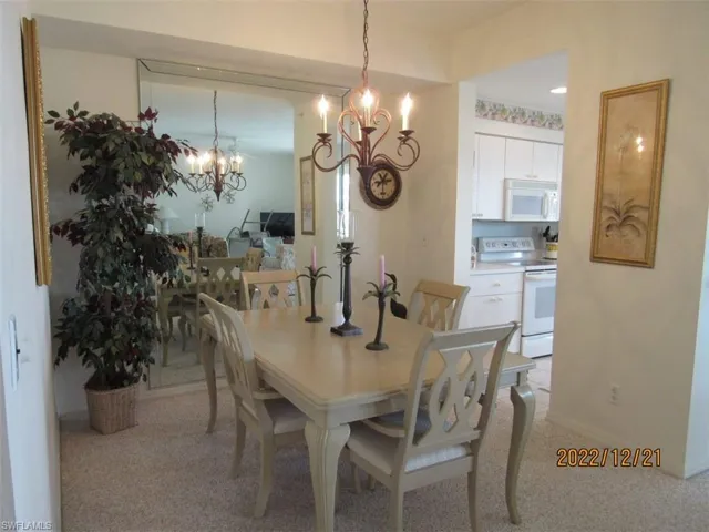 Dining space featuring a chandelier, light carpet, and baseboards