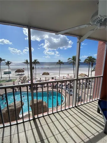 Balcony with a view of the beach, a water view, and ceiling fan