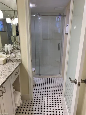 Bathroom with vanity, tile patterned floors, toilet, and an enclosed shower