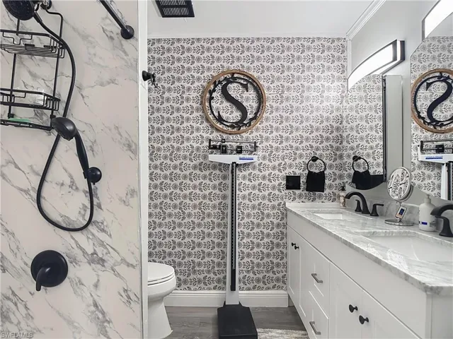 Bathroom featuring a dual-sink vanity with white cabinetry and a stone countertop, individual mirrors, and matte black fixtures