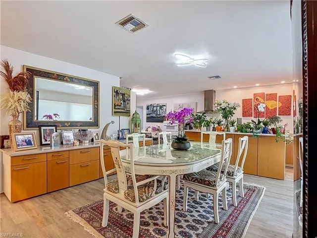 Open-concept dining area featuring wood-finish flooring, a contemporary dining table, and a built-in sideboard with a stone-finish countertop