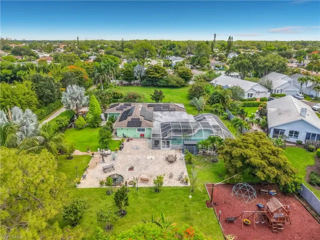 Expansive backyard featuring a screened-in pool enclosure, a large paved patio, and mature landscaping