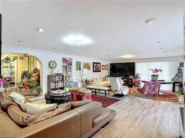 Spacious room featuring wood-finish flooring, recessed lighting, and an arched entry