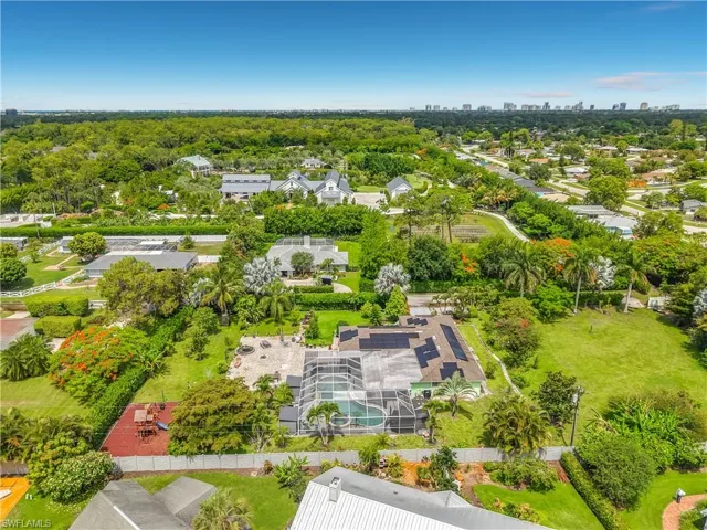 Expansive property featuring a screened-in pool, multiple structures, established landscaping, and a manicured lawn