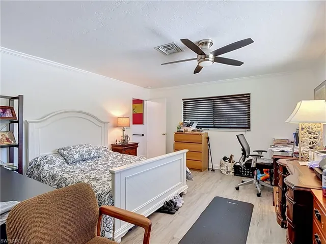 Interior space featuring wood-finish flooring, a contemporary ceiling fan with integrated lighting, window blinds, and white crown molding
