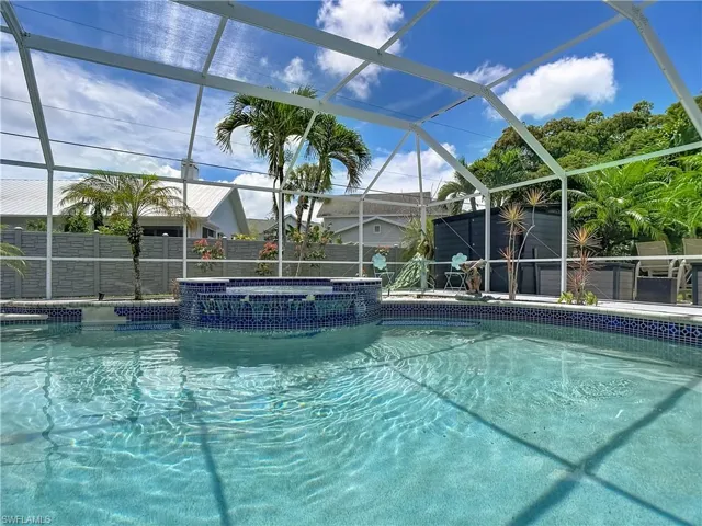 Screened-in pool area featuring a built-in spa with blue mosaic tiling and a waterfall feature