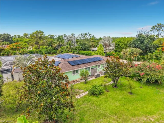 Single-story residence featuring a screen-enclosed pool structure, roof-mounted solar panels, and a surrounding lawn with mature landscaping