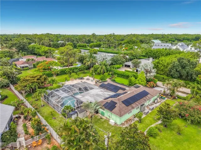 Aerial perspective showcasing a single-story residence with multiple solar panel installations