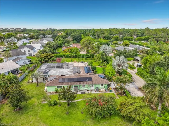 Expansive property featuring a green-toned exterior, a caged swimming pool, and a brown shingle roof with solar panels